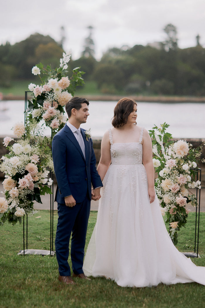 Couple beside a blush floral backdrop on the Harbour View Lawn