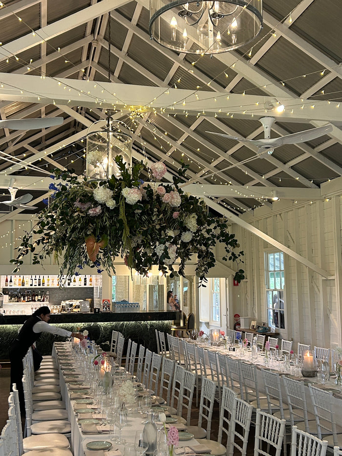 Long banquet tables under a hanging floral installation at Athol Hall