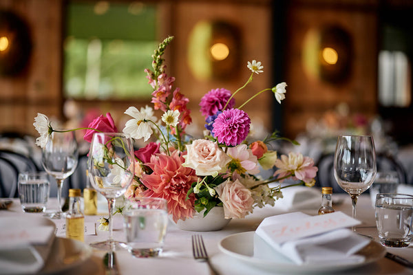 low table arrangement flowers in a ceramic vase on a table for a wedding reception inside barn bendooley estate southern highlands