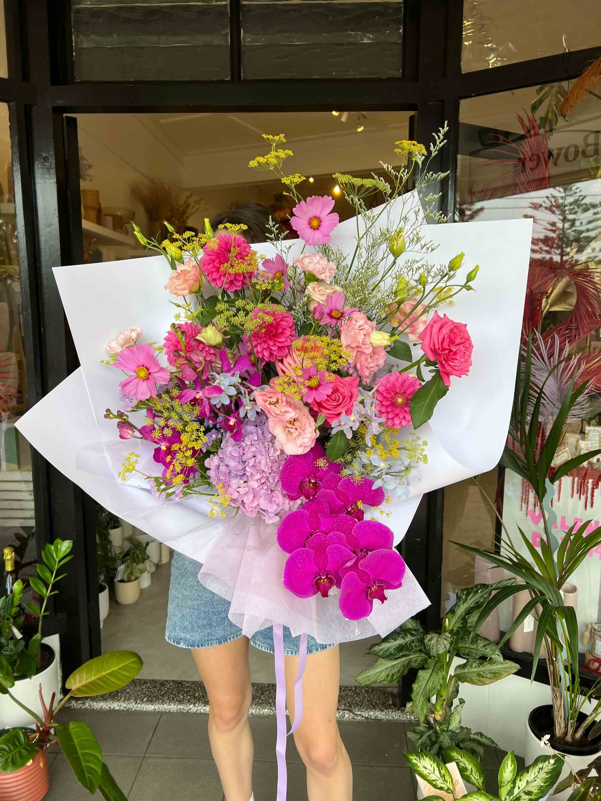 bright pink colourful flowers wrapped in paper for bouquet delivery seasonal flowers florists choice