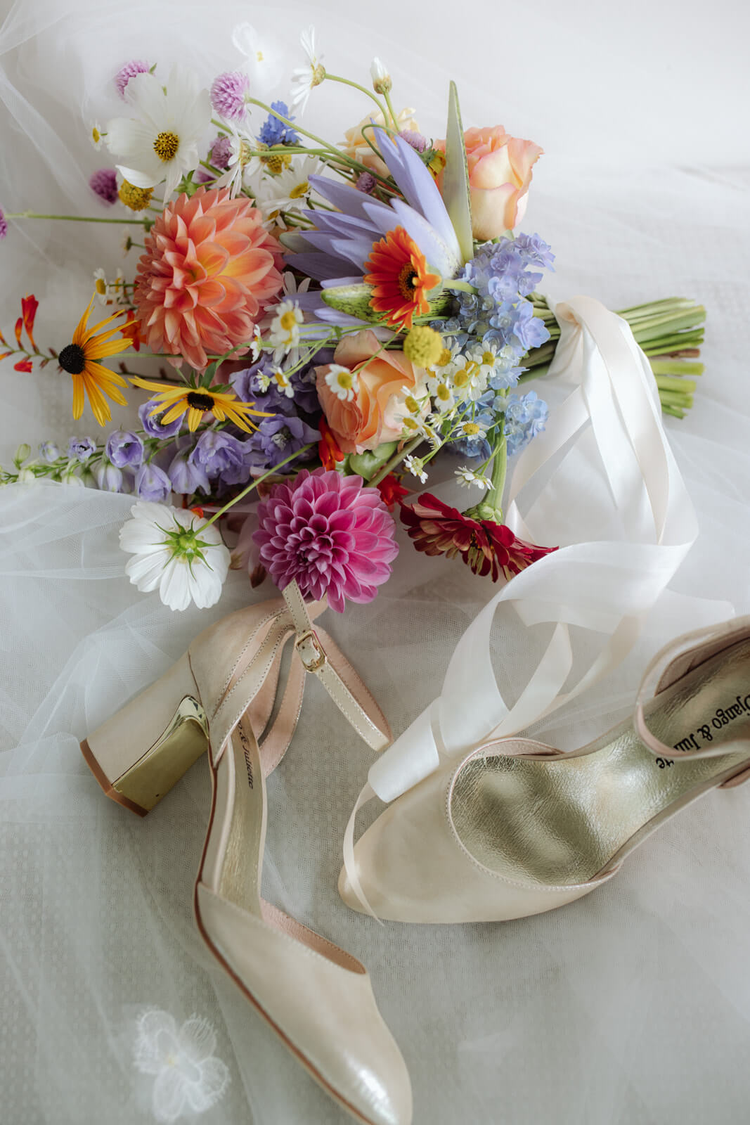 whimsical garden colourful bridal bouquet with white wedding shoes
