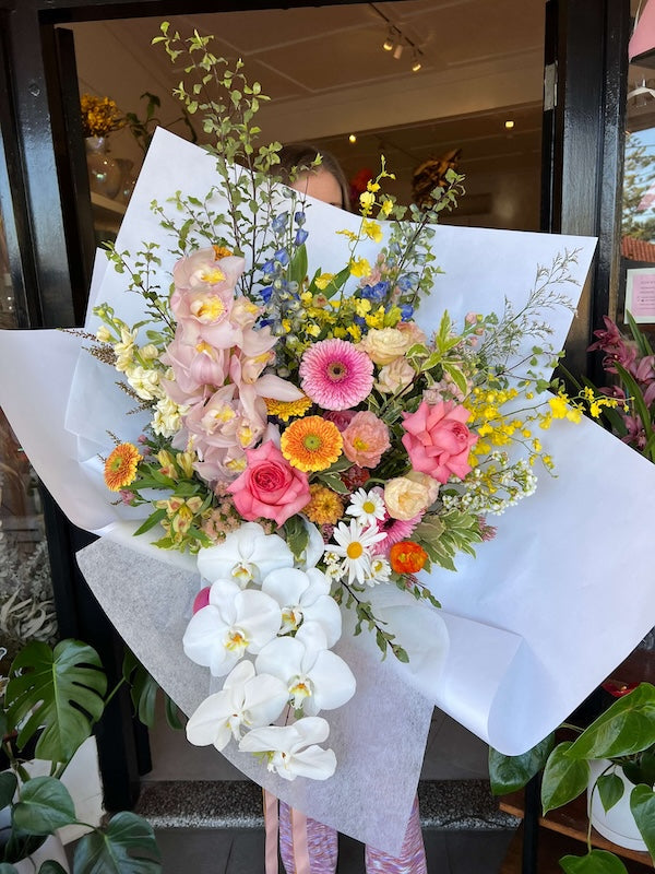 Bouquet of colourful fresh flowers with white orchids on a white paper background