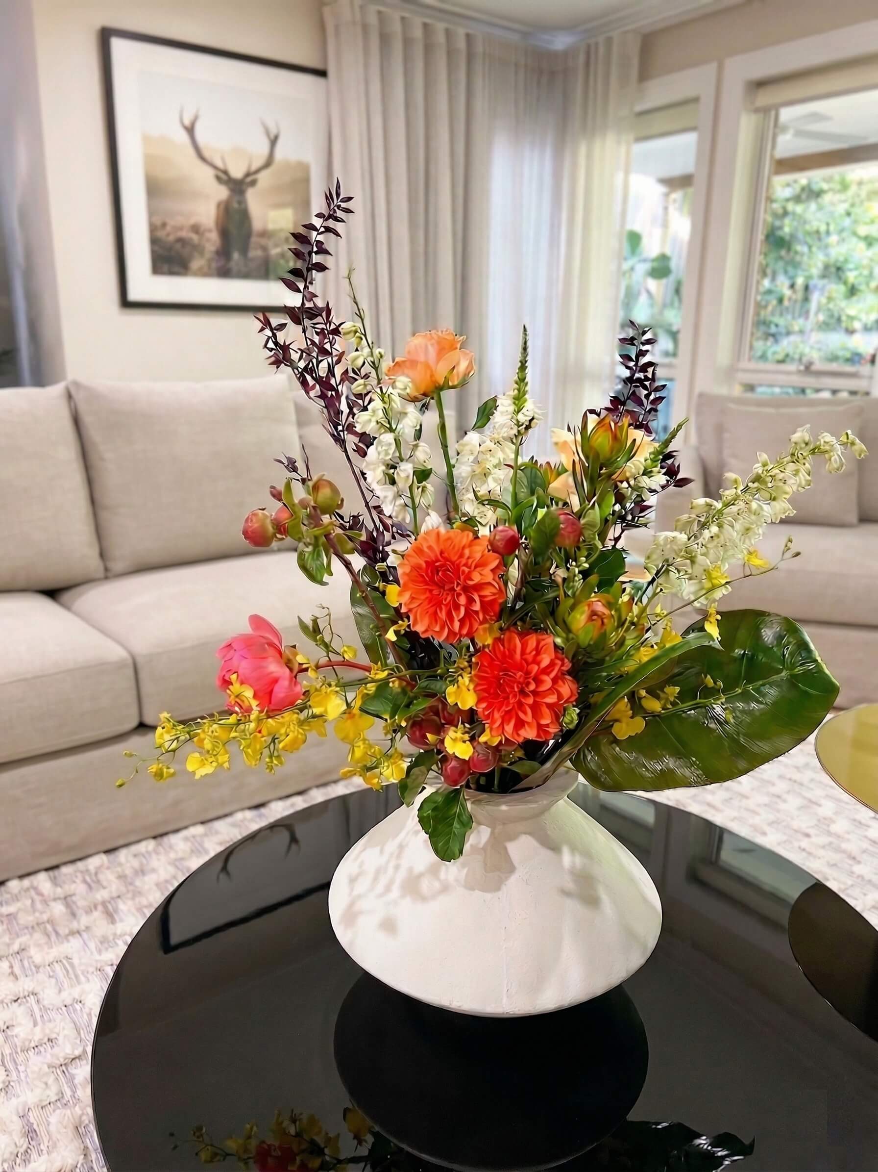 Colourful modern flower arrangement in a white vase on a coffee table in a living room for real estate open home styling