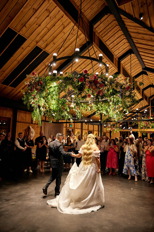 couple on dance floor at bendooley book barn wedding underneath ceiling flowers installation